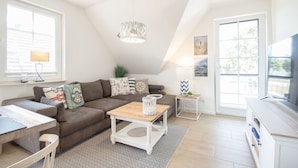 Een moderne woonkamer met een bruine bank, een houten salontafel, een witte bijzettafel en een tv-meubel.