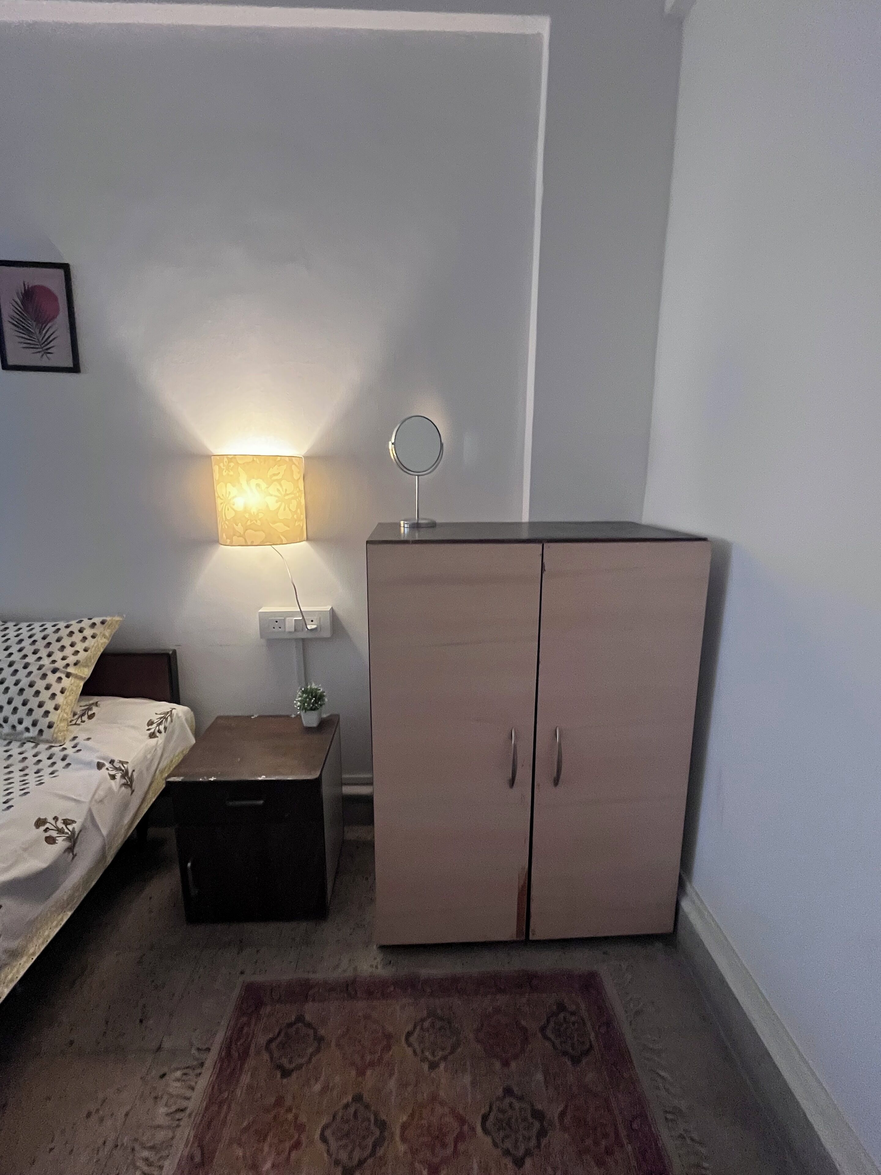 Ett sovrum med en säng, ett nattduksbord, en lampa och en garderob.