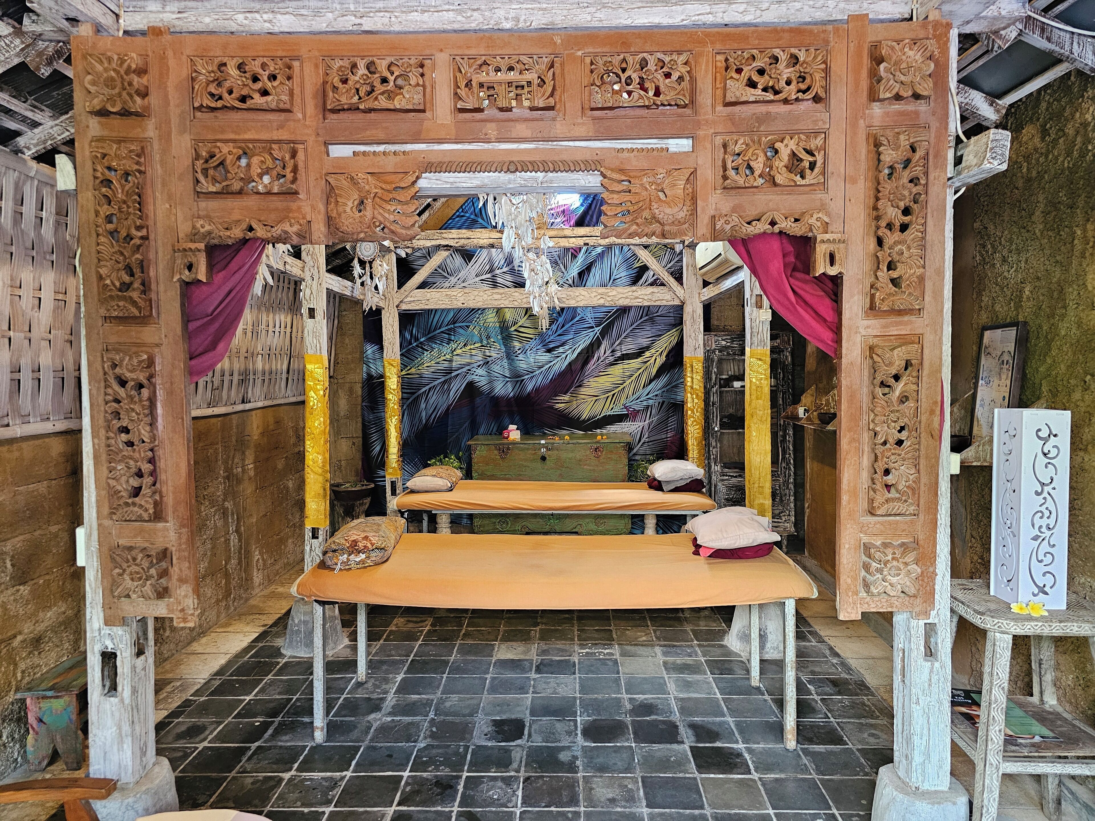 A room with a bed, a small table, and a decorative wooden structure with intricate carvings.