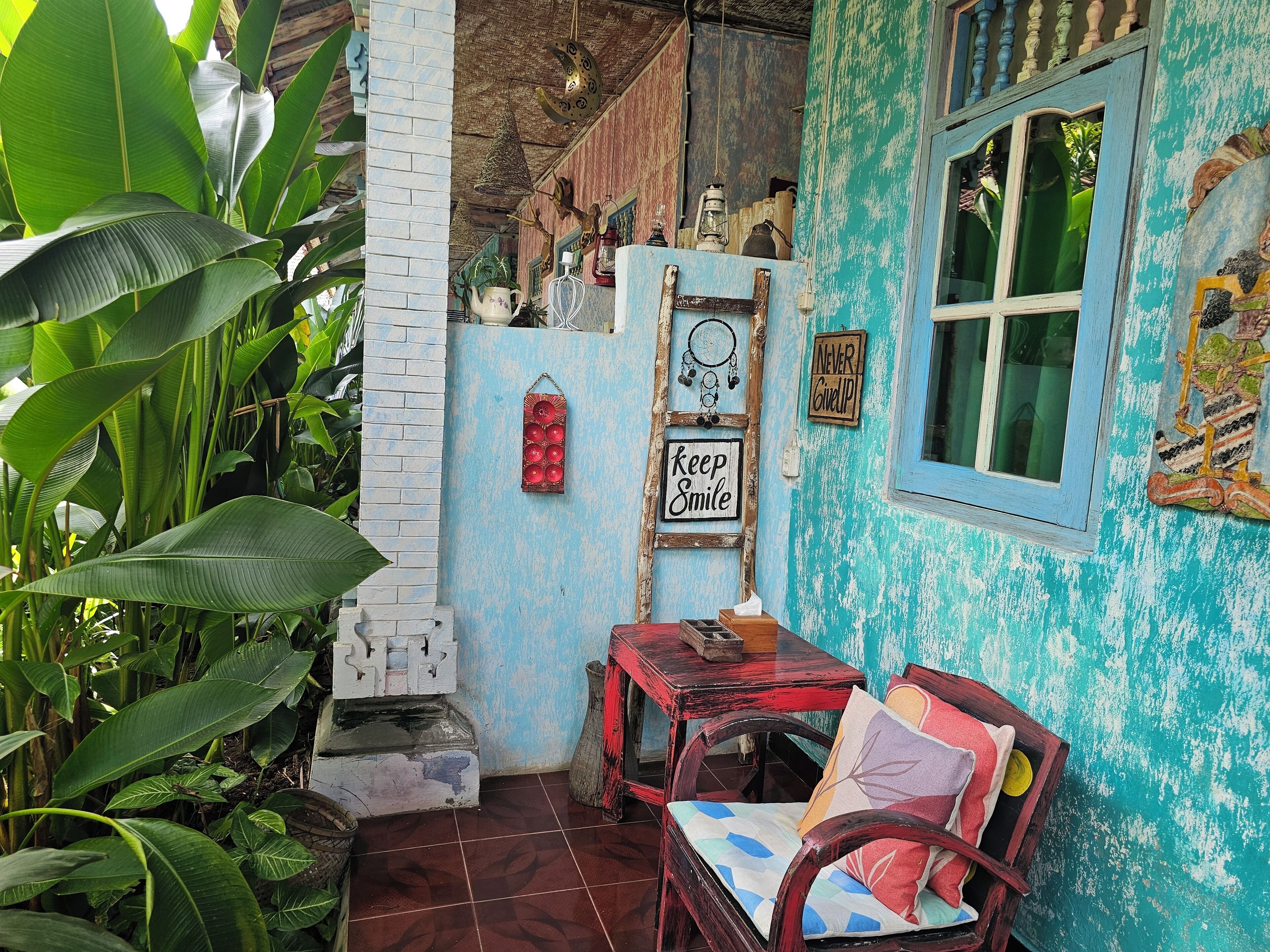 Una habitación rústica con una pared azul, una silla de madera, una mesita pequeña y una ventana.