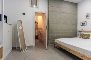 Ein Schlafzimmer mit einem Bett, einem Kleiderschrank und einem an der Wand lehnten Spiegel.