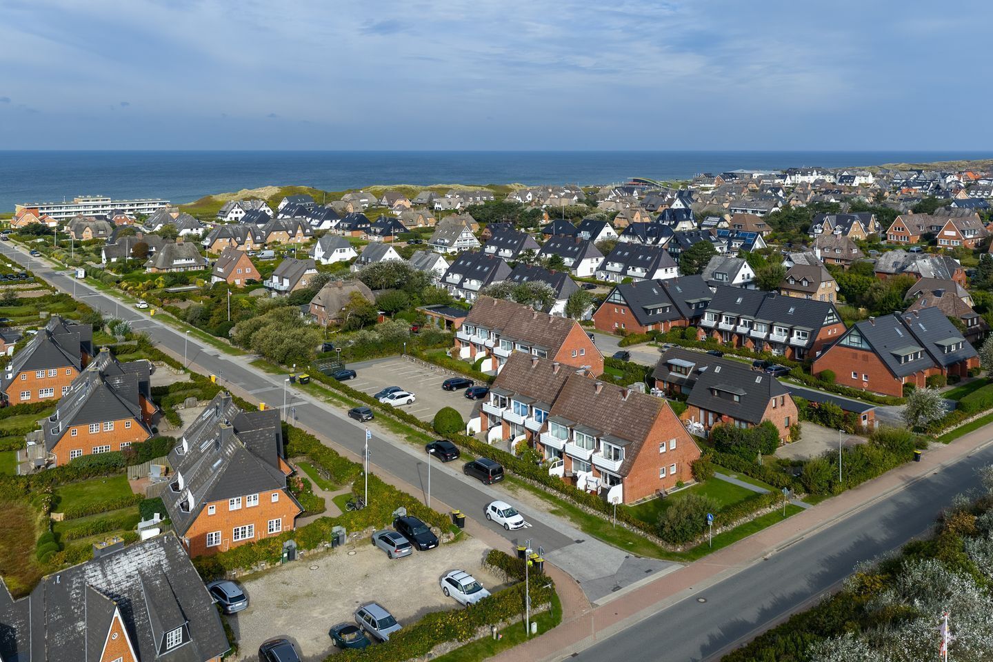 Vista aérea de una zona residencial con casas, una carretera y una masa de agua al fondo.