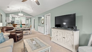 A spacious living room with a large flat-screen TV, leather recliner, and a wooden coffee table. - Charming upgraded 2-bed condo in amazing Pawleys Island True Blue Golf Course (Pawleys Island)