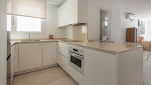 Eine moderne Küche mit weißen Schränken, einem Einbauofen und einem Fenster für natürliches Licht.