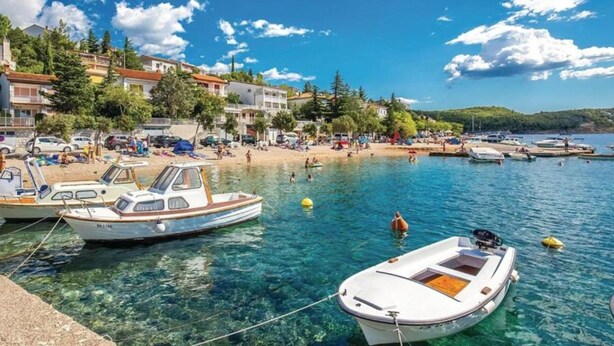 A coastal area with boats docked, a sandy beach, and buildings along the shore. - Apartmani Jadranovo Mare (Crikvenica)