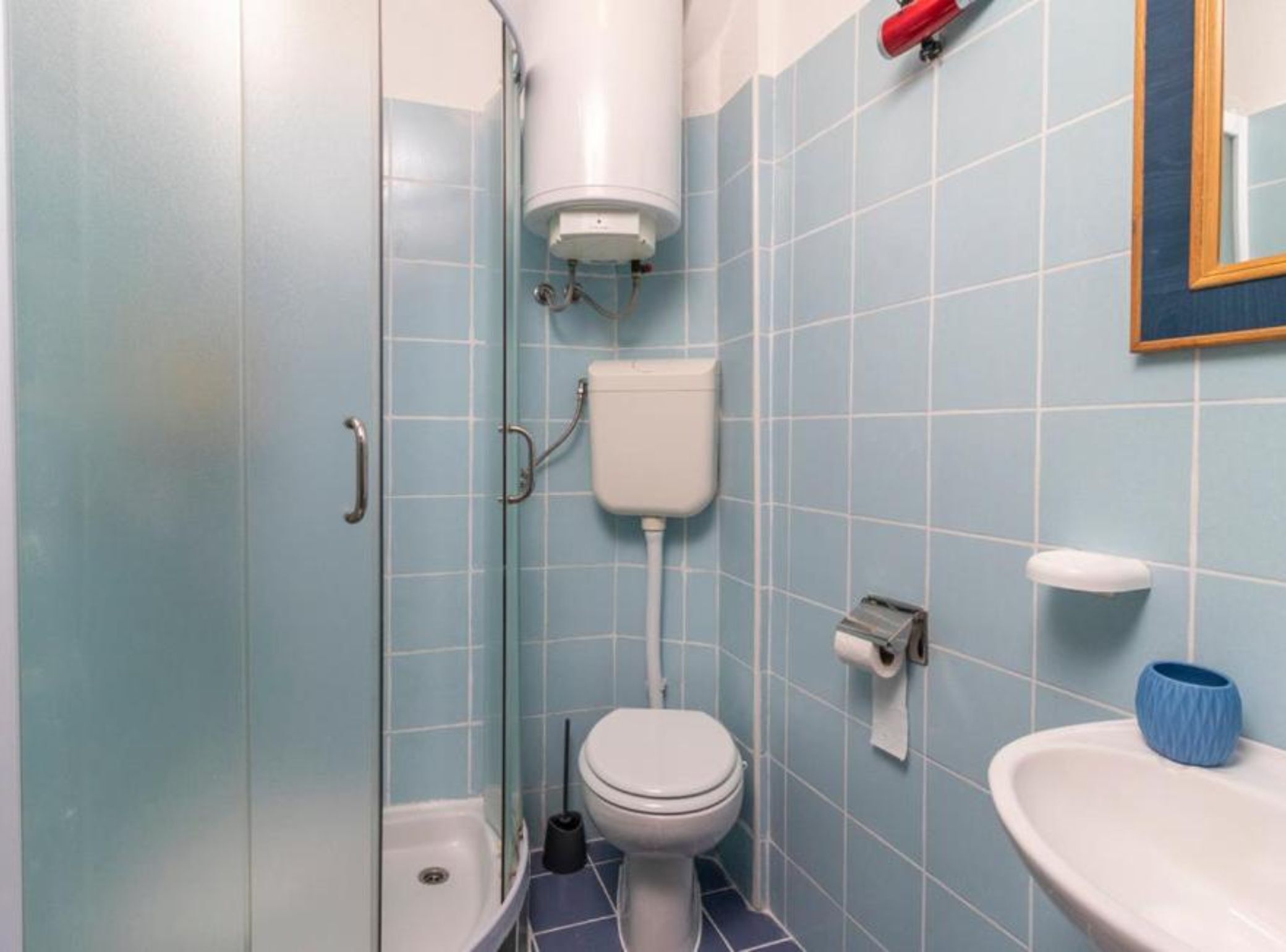 A bathroom with a toilet, sink, and shower.