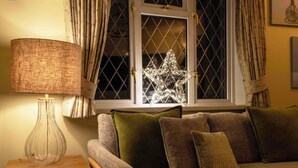 Una sala de estar acogedora con un sofá, una lámpara y un adorno de estrella en la ventana.