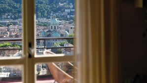 Vista a través de una ventana de un paisaje urbano donde destaca una iglesia con cúpula verde.