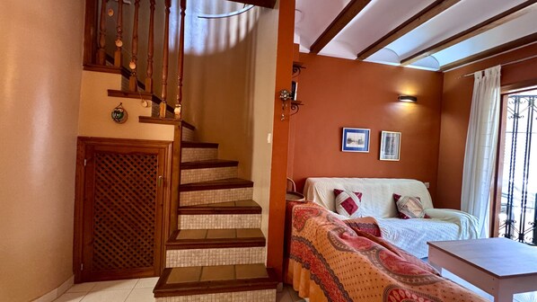 A bedroom with a bed, a wooden staircase, and a small table.