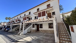 A multi-story building with a central staircase, balconies, and a parking area.