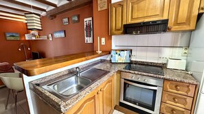 A kitchen with granite countertops, a stainless steel sink, wooden cabinets, a built-in oven, and a black range hood. - Bahia Azul -11   VYBDenia (Denia)