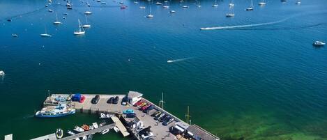 An aerial view of a marina with numerous boats docked and a small building with a parking area.