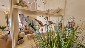 Un salon comprenant un canapé, une table basse et des objets décoratifs, notamment une sculpture d’oiseau et une plante.