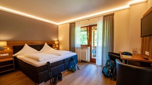 A hotel room with a bed, bedside tables, a desk, a chair, and a TV.