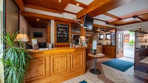 A reception area with a wooden counter, a chalkboard menu, and a television mounted on the wall.
