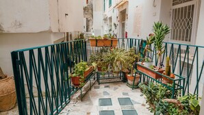 A narrow courtyard with a metal railing, potted plants, and a tiled floor. - rita's house (Atrani)