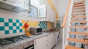 A kitchen with a gas stove, microwave, and a washing machine. - rita's house (Atrani)