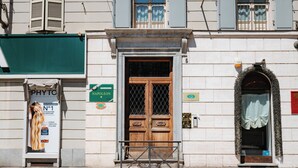 A building facade with a wooden door, a green awning, and a sign for a pharmacy.