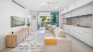 A modern kitchen with white cabinets, a marble countertop, and a ceiling fan.