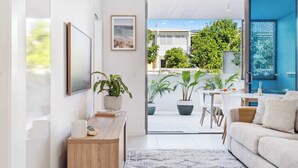 A modern living room with a sofa, a coffee table, and a view of the outdoor patio area.