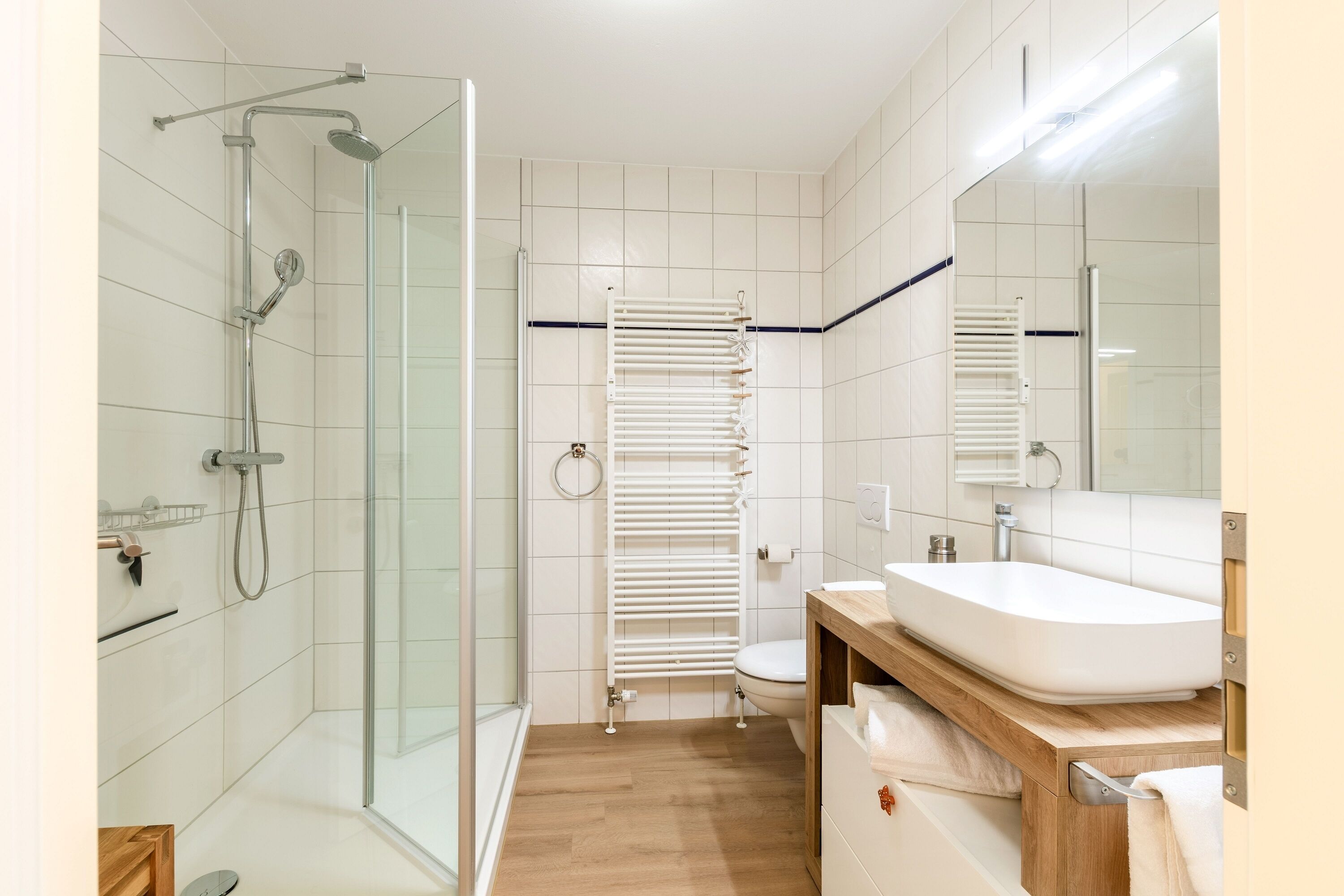 Une salle de bain moderne avec une douche à parois de verre, des toilettes blanches et un meuble-lavabo en bois avec un évier.