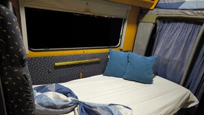 A compact bed with a headboard, a window, and a curtain.