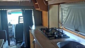A compact RV kitchen with a stove, sink, and cabinets.