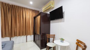 A room with a bed, a small table with chairs, a TV mounted on the wall, and an air conditioning unit. - Sabai Stay (Hua Hin)