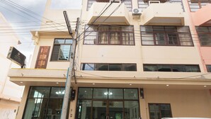 A multi-story building with a ground-level entrance, potted plants, and a parked white SUV. - Sabai Stay (Hua Hin)