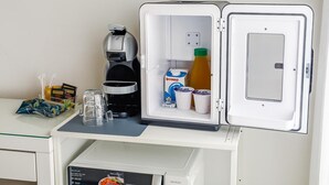 A compact refrigerator with a coffee maker, a carton of milk, and a bottle of orange juice. - Vatican LeM affittacamere (Rome)