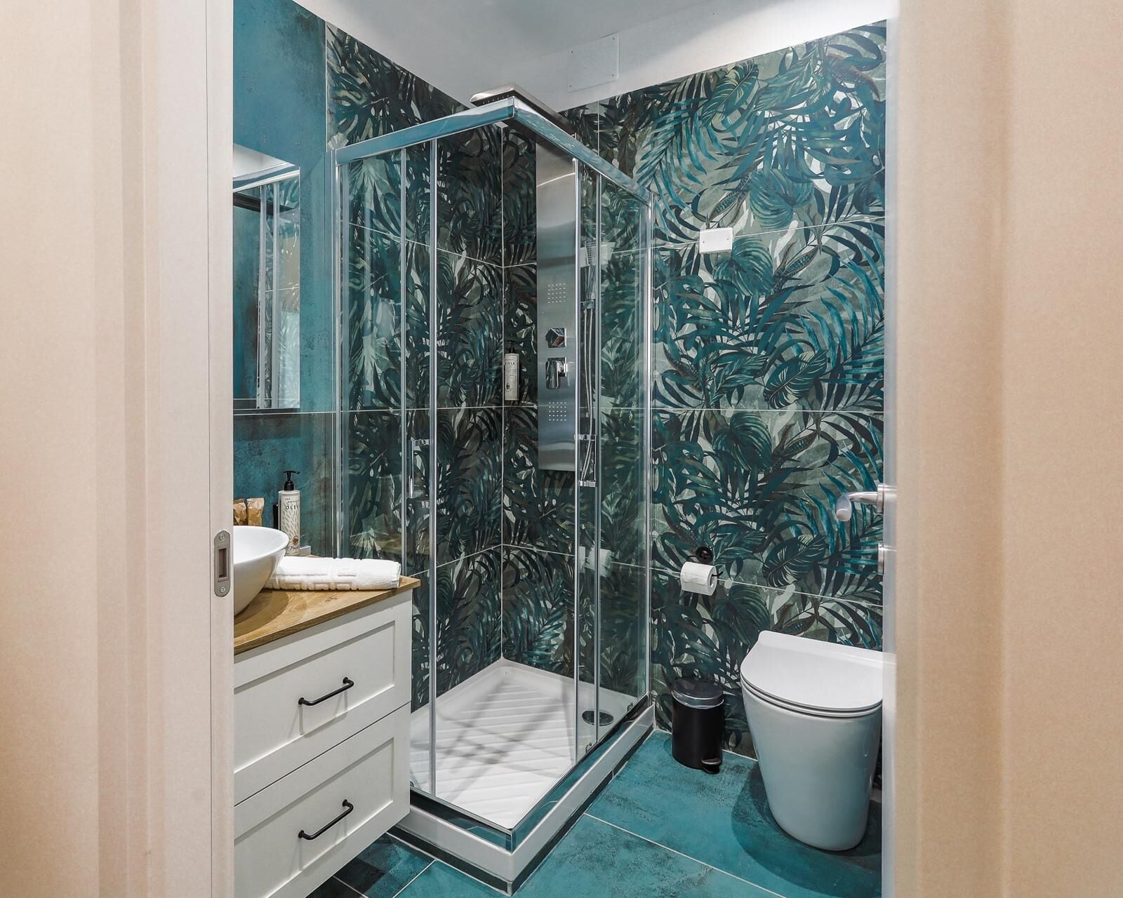 A bathroom with a glass shower enclosure, a white sink, and a toilet.