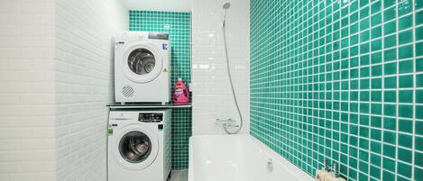 A bathroom with a washing machine, a bathtub, and a shower.
