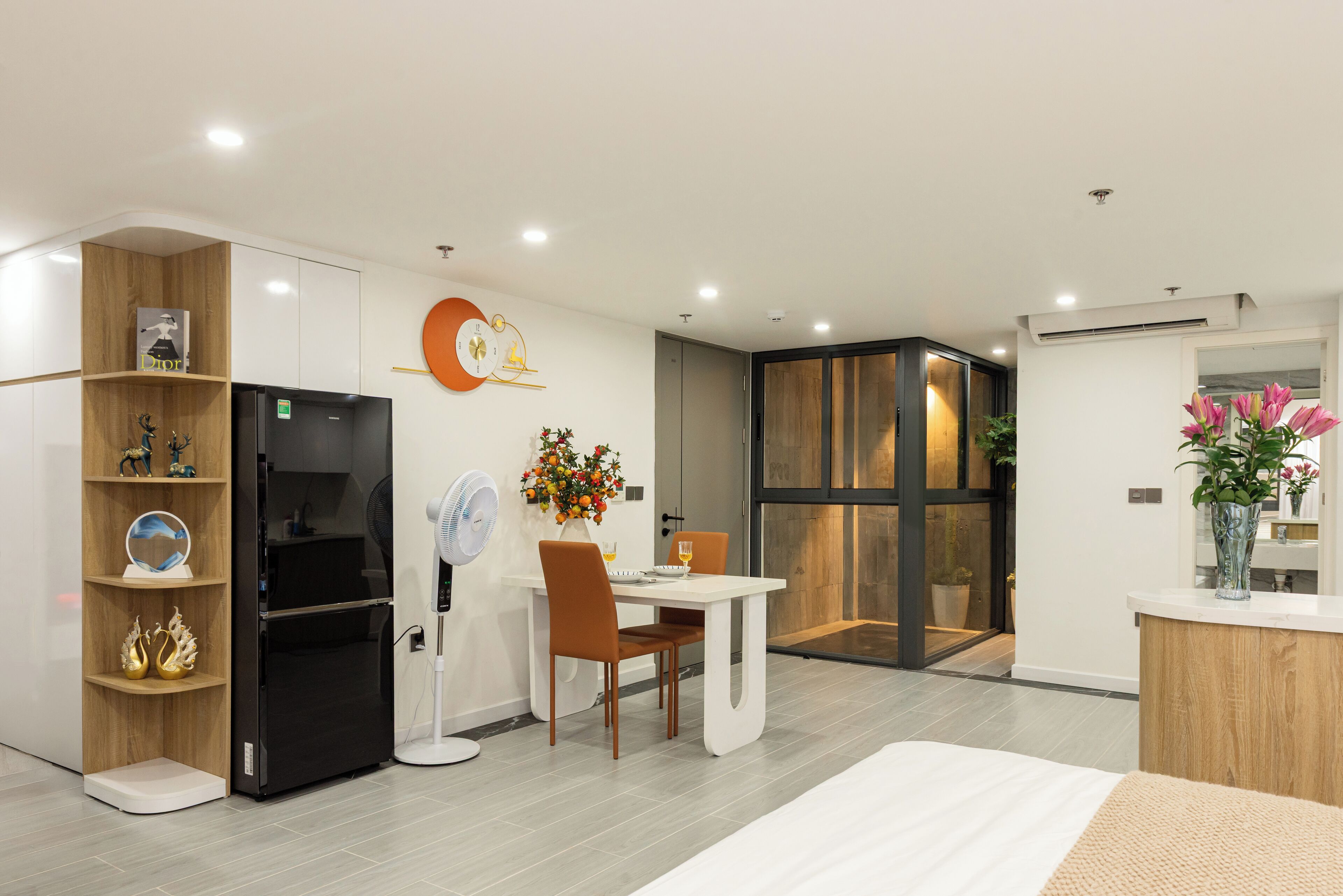 A modern kitchen with a black refrigerator, white cabinets, and a wooden shelf unit.