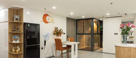A modern kitchen with a black refrigerator, white cabinets, and a wooden shelf unit.