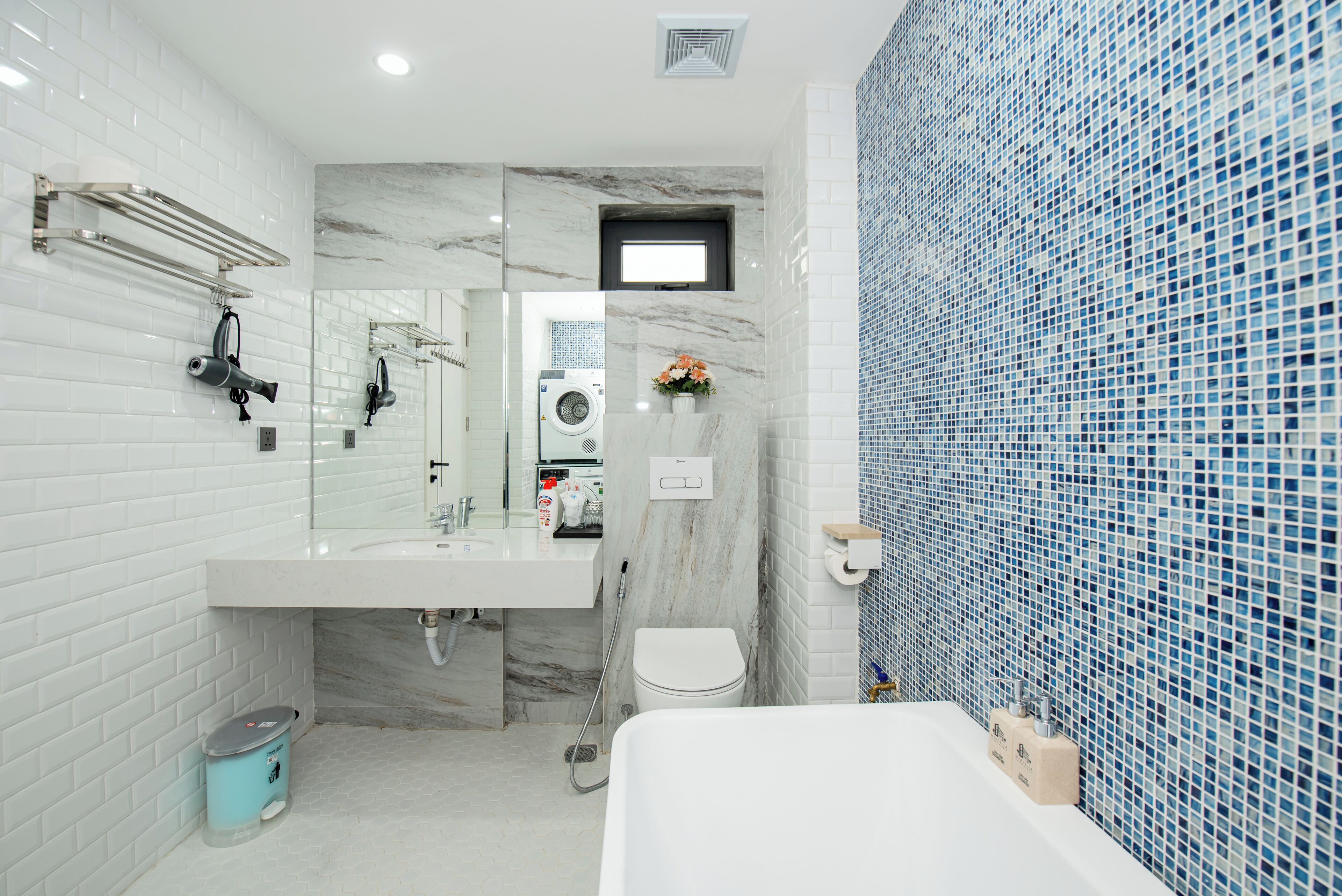 Une salle de bain moderne avec un lavabo blanc, un miroir, des toilettes et une baignoire.