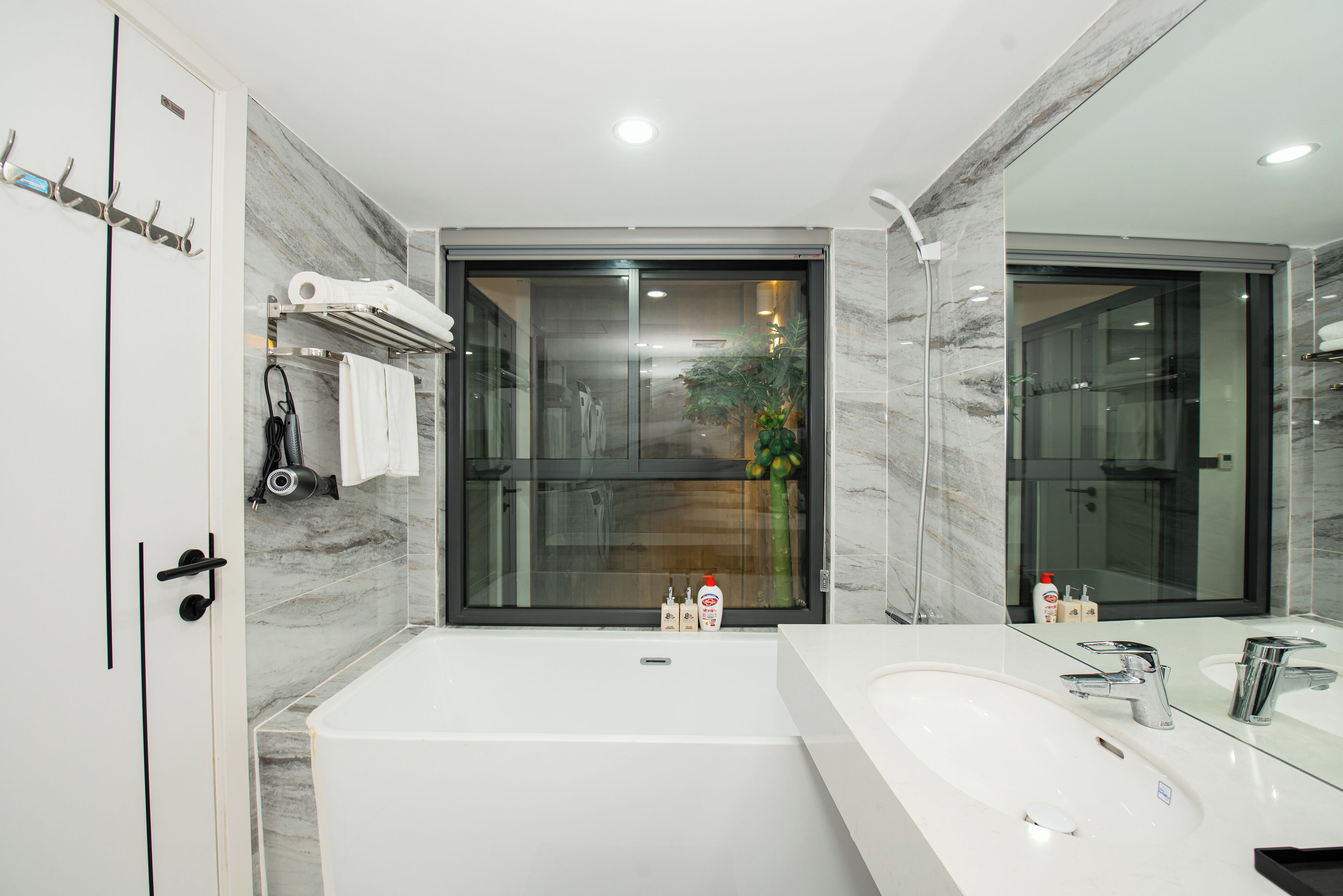 A modern bathroom with a large bathtub, a double sink, and a glass shower enclosure.