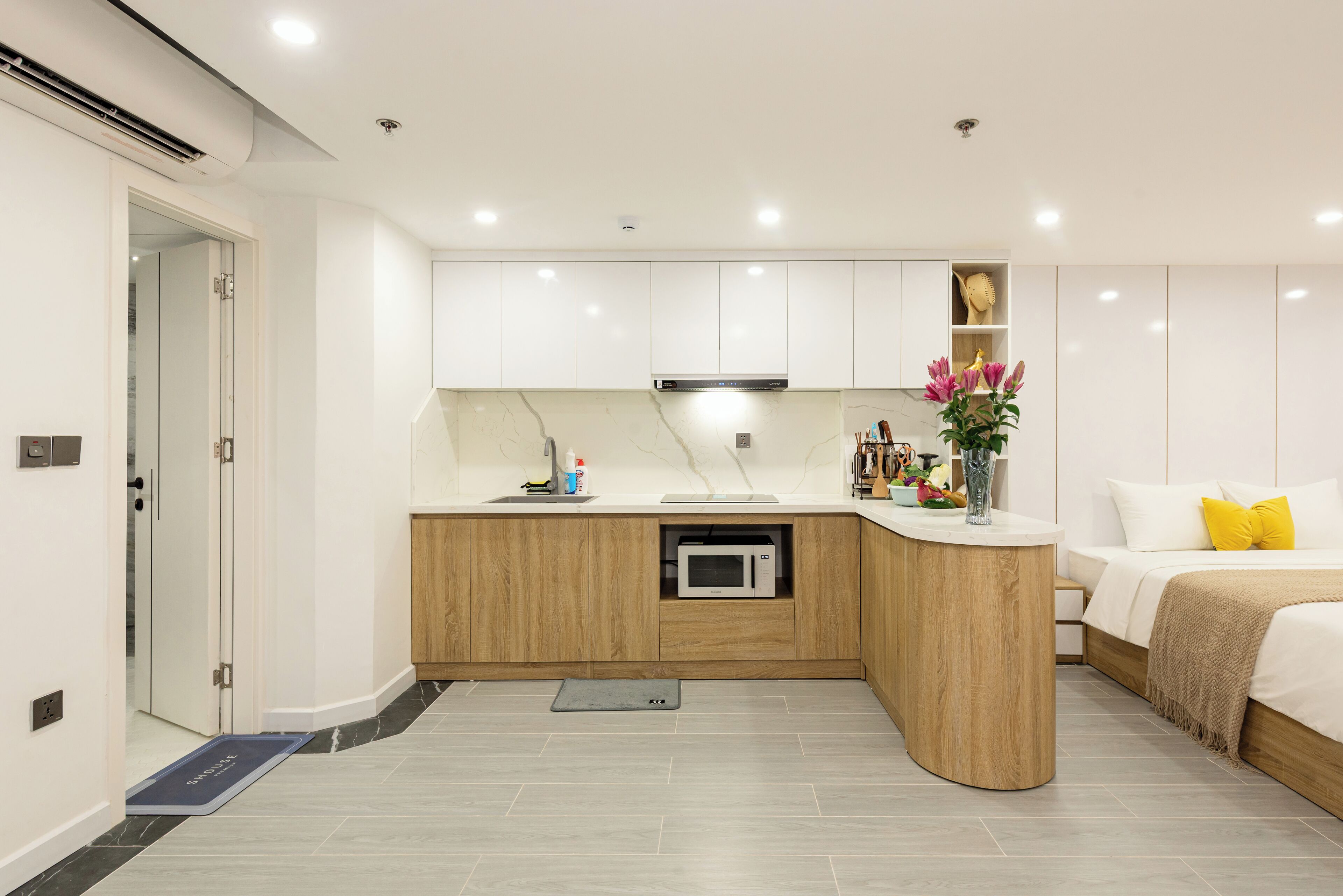 A modern kitchen with white cabinets, a built-in microwave, and a wooden countertop.
