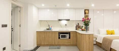 A modern kitchen with white cabinets, a built-in microwave, and a wooden countertop.