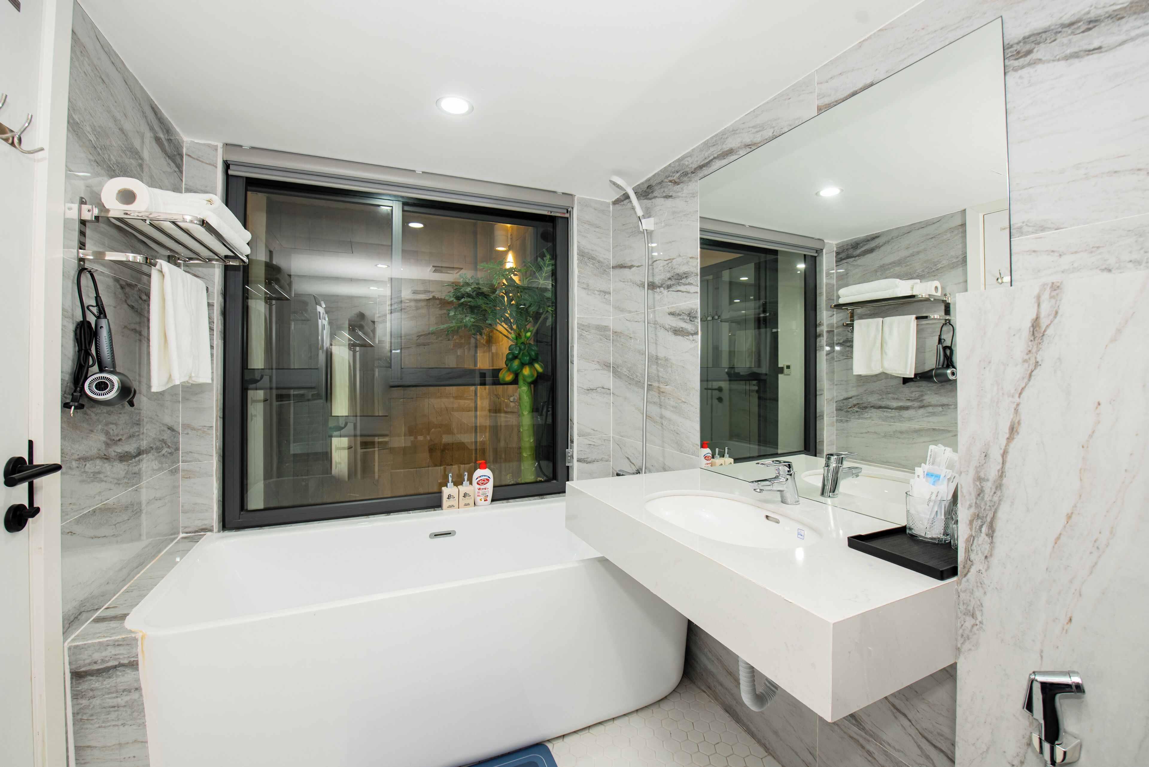 A modern bathroom with a large bathtub, a double sink, and a large mirror.