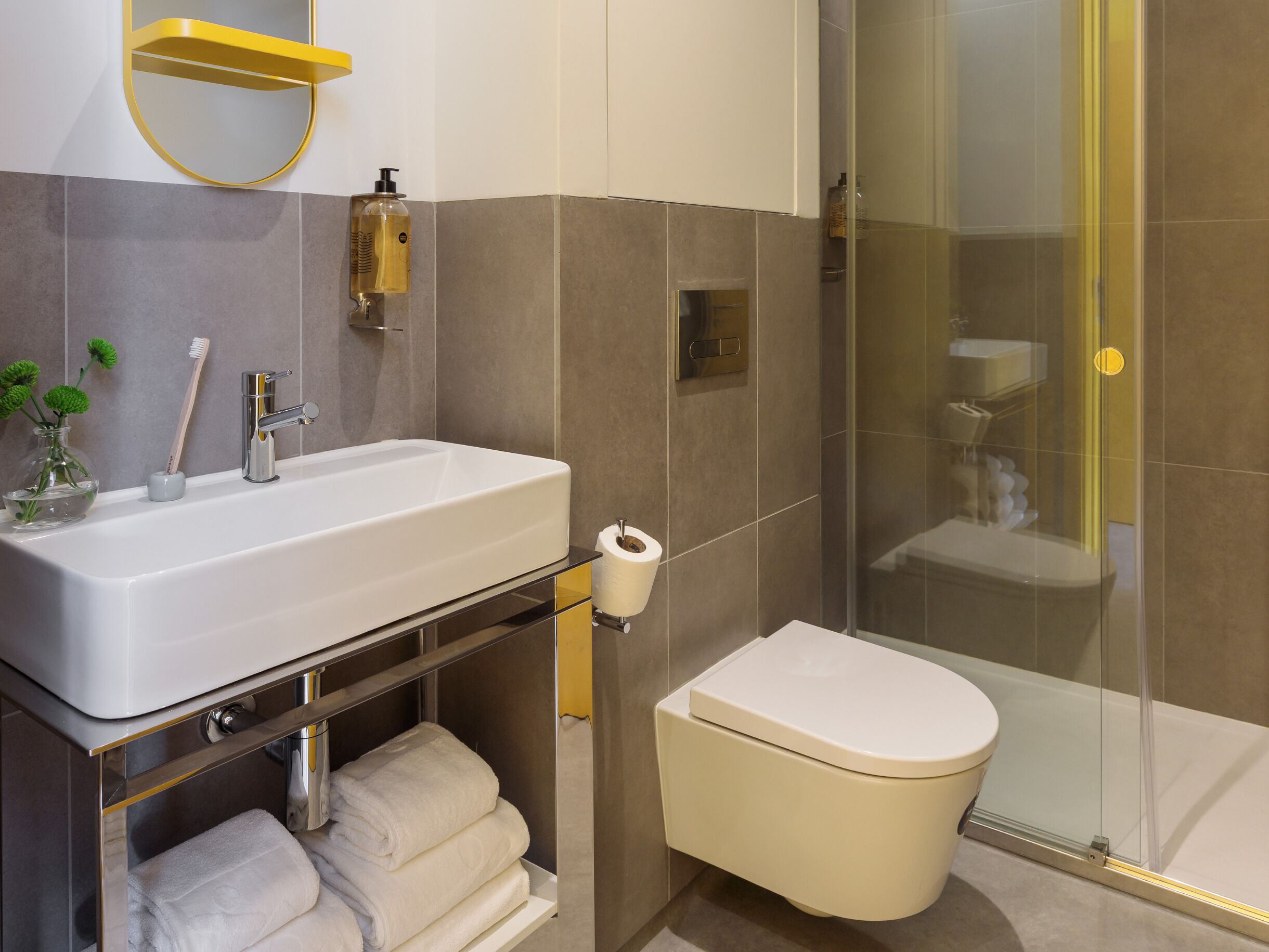 A modern bathroom with a white sink, a glass shower enclosure, and a toilet.