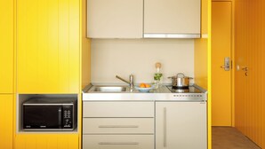 A compact kitchen with yellow cabinets, a microwave, a sink, and a stove.