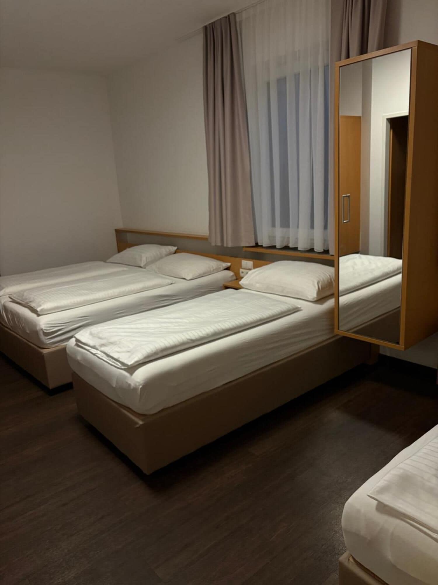 Una habitación con dos camas, un armario de madera y un espejo.