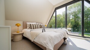 A bedroom with a bed, bedside table, lamp, and large window with a view of greenery. - Stay in complete comfort in this modern, recently built holiday home with beautiful views of the wat (Oude-Tonge)
