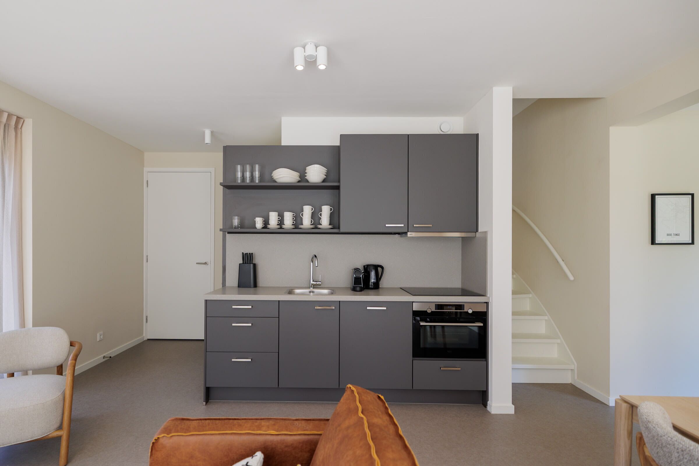 A modern kitchen with grey cabinets, a white countertop, and a built-in oven.