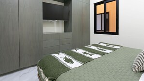 Een slaapkamer met een bed, een aan de muur bevestigde televisie en een raam met uitzicht.