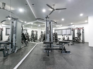 A modern gym with various weightlifting equipment, mirrors, and ceiling fans. - Casa Lumar in Cabo San Lucas (Cabo San Lucas)