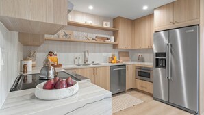 A modern kitchen with wooden cabinets, stainless steel appliances, and a marble countertop. - Modern 5BDR, Mins to Sunset Cliffs & Ocean Beach | Point View Luxe by AvantStay (San Diego)