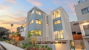 A modern two-story residential building with a balcony, surrounded by a landscaped garden with various plants and flowers. - Modern 5BDR, Mins to Sunset Cliffs & Ocean Beach | Point View Luxe by AvantStay (San Diego)