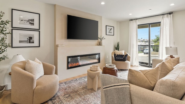 A modern living room with a fireplace, comfortable seating, and a large TV. - Modern 5BDR, Mins to Sunset Cliffs & Ocean Beach | Point View Luxe by AvantStay (San Diego)
