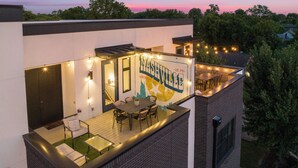 Eine Dachterrasse mit Außenbestuhlung, Lichterketten und einem Wandbild.